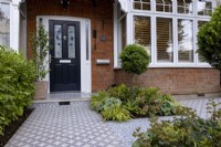 Suburban front garden with decorative tile pathways surrounding shade tolerant plants