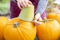 Using pot and pencil to mark a circle on the pumpkins
