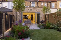 Suburban garden in London with lighting, with view towards house and kitchen