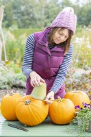 Woman using pot and pencil to mark a circle on the pumpkins