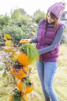 Woman placing a pumpkin top over the plants on the top pumpkin