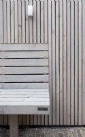 Special designed wooden bench at wooden fence. Lighting at fence.