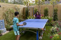 Mother playing table tennis with her son their West London garden