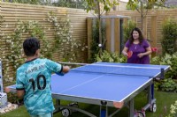 Mother playing table tennis with her son their West London garden