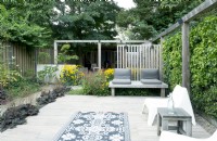 Terrace with wooden pergola, wooden benches and garden carpet.