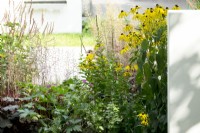 Rudbeckia, Persicaria and Erodium in the border with wall divider.
