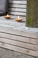 Two types of lighting on lounge bench, one insert plus candles in terracotta holders.