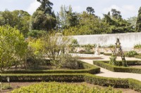  View over plant beds edged with Box towards wall with raised beds. The Botanic Garden. Queluz, Lisbon, Portugal, September. 