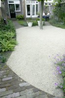 Overview of narrow garden with gravel patio creating an open space in the middle.