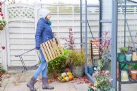 Woman storing wooden furniture in greenhouse