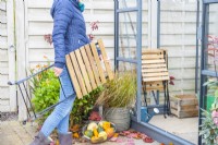 Woman storing wooden furniture in greenhouse