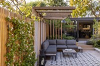 Pergola and patio in contemporary garden with view towards garden room or office