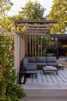 Pergola and patio in contemporary garden with view towards garden room or office