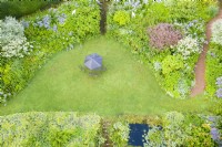 View over lawn and borders with parasol and chairs on lawn; image taken with drone. July. Summer.