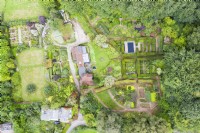 View over whole garden and surrounding woodland with house in centre of image; image taken with drone. September. Summer.