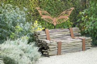 Bench of branches held together with corten steel and corten steel butterfly.