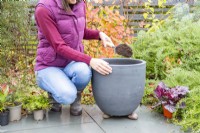 Woman placing a layer of compost in the container