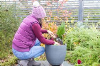 Woman filling in any gaps in the container with compost