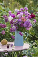 Mixed Scabious, Zinnia and Dianthus displayed in blue enamel jug on table