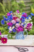 Mixed flower arrangement in pottery jug on tray - Scabious; Centaurea cyanus; Lathyrus; Ammi and Cosmos