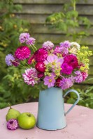Mixed bouquet of flowers - Cosmos, Dahlias, Achemilla mollis, Scabious and Helichrysums in blue enamel jug on table