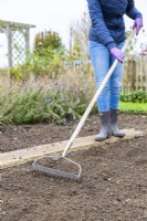 Woman using a rake to level out soil