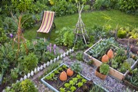 Vegetable beds, flowerbeds and lawn with a deck chair.