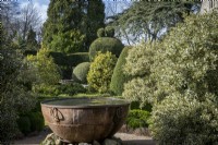 Topiary garden in early spring.  Large copper urn container as focal point