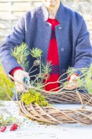 Woman using snips to cut pine branches into smaller pieces
