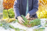 Woman placing conifer branches on the wreath
