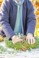Woman placing Eucalyptus branches on the wreath