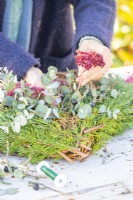 Woman placing dried Sedum flowers in wreath