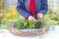 Woman adding red berries to the wreath