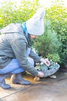 Woman planting bulbs in between plants in the container