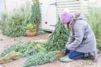 Woman using secateurs to cut conifer branches down to size