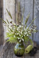 Spring posy with salad Rocket flowers, Sorbaria foliage and Sweet Vernal Grass flowers. In green glass vase.