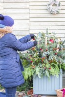 Woman placing baubles on the sprigs in the container