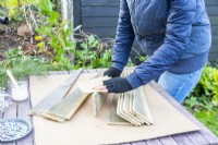 Woman sanding the edges of the newly sawn wooden planks
