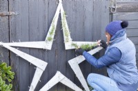 Woman placing Cedar sprigs on the wooden star
