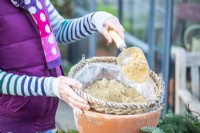 Woman placing sand in the hanging basket