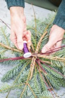 Woman wiring the two pine arrangements together