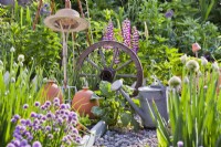 Tools in potager garden - watering can, terracotta forcer, old wheel and garden fork.
