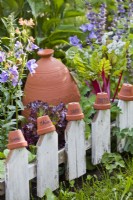 Low fencing with terracotta pot labels in small kitchen garden.