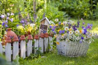 Basket with wildflowers beside small kitchen garden.