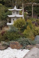 Japanese pagoda lantern surrounded by conifers, rocks and white gravel