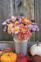 Chrysanthemums and purple Hydrangeas arranged in small metal pot against wooden background