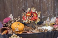 Autumnal arrangement in metal tray with squashes, orange Helichyrsums, berries and dried Hydrangeas and seedheads, foliage and terracotta pots
