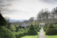 View west across the formal garden at Perrycroft, Herefordshire in March featuring clipped yews and box parterres
