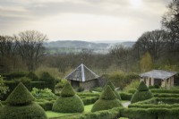View west across the formal garden at Perrycroft, Herefordshire in March featuring clipped yews and box parterres