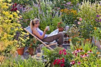 Woman relaxing on patio drinking tea and reading  garden magazine.